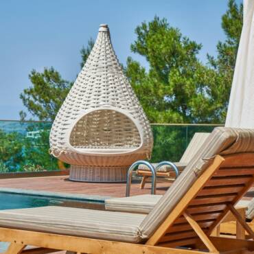 Elegant poolside setting featuring modern loungers and a unique woven chair in a tropical resort.
