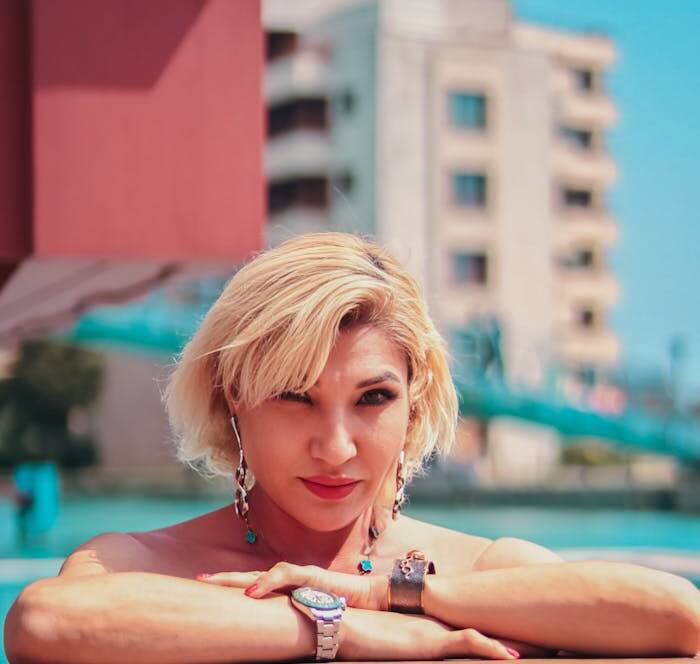 A blonde woman enjoys a sunny day poolside in an urban environment. Summer vibes.