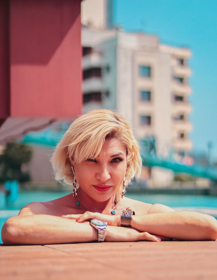 A blonde woman enjoys a sunny day poolside in an urban environment. Summer vibes.