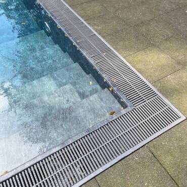 A detailed view of a swimming pool edge with modern design elements, located outdoors.
