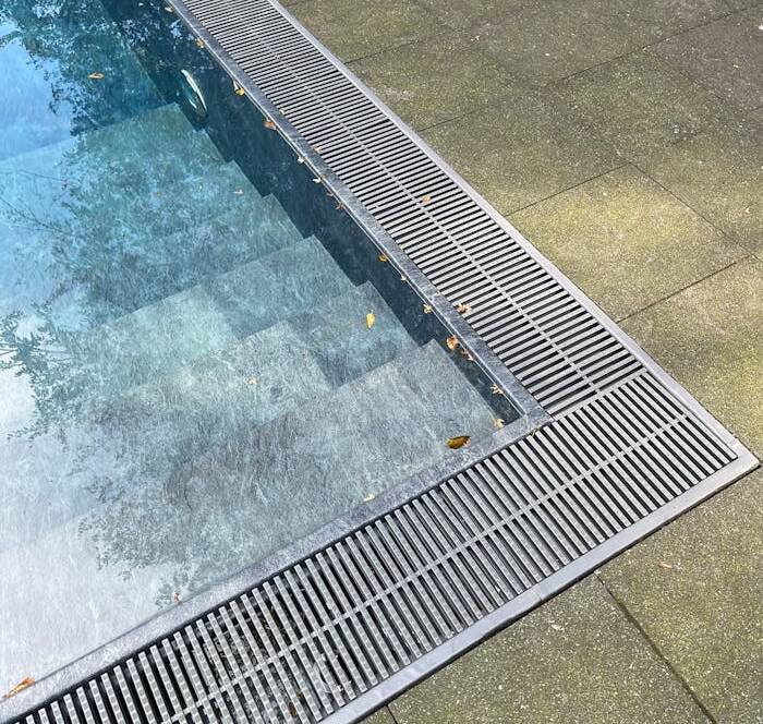 A detailed view of a swimming pool edge with modern design elements, located outdoors.